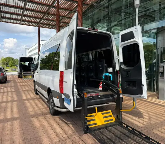 Professionele rolstoeltaxi chauffeur helpt klant in Huizen